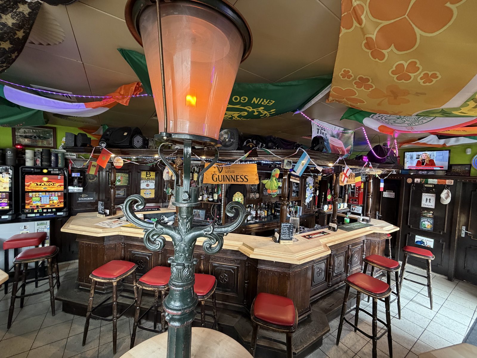Blick auf die Bar des Green Goose Pub mit Laterne, Guinness-Schild und Länderflaggen